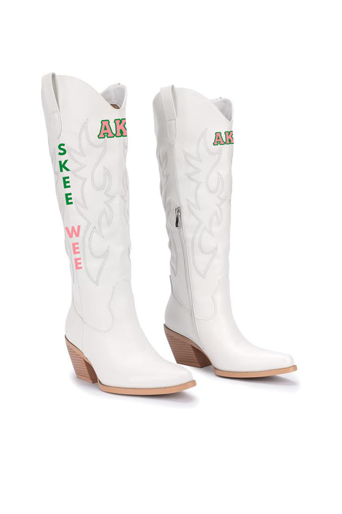 A pair of white western cowboy boots with decorative stitching, featuring 'SKEE WEE' text in green and pink on one boot and 'AKA' in green and pink on the other. Sorority Boots